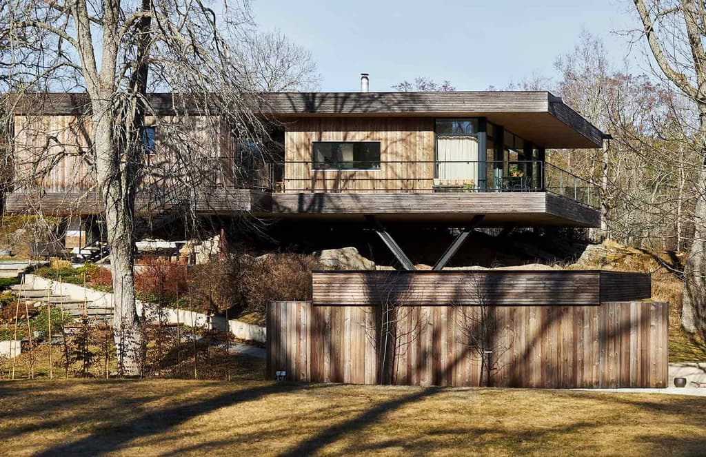 A minimalist Swedish home floats above a rocky outcrop in Värmdö