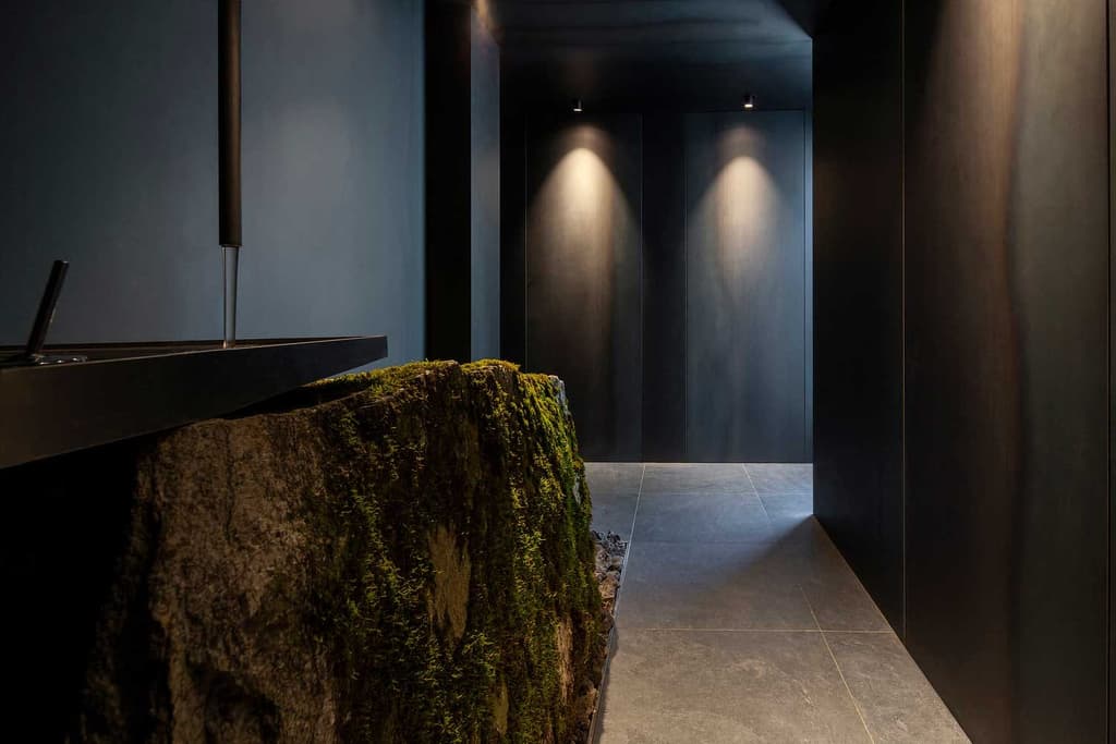 The bathroom features a sink that rests atop a moss-covered boulder