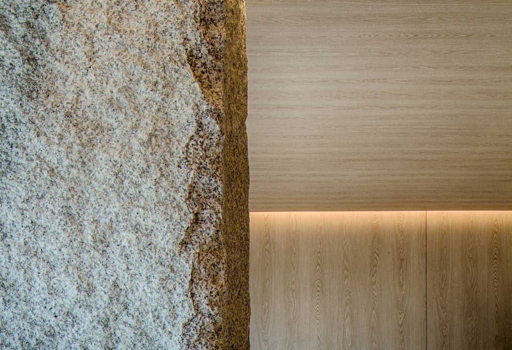 A stone pillar juts into the yoga studio offering structural support for the building and connecting the manmade with the natural