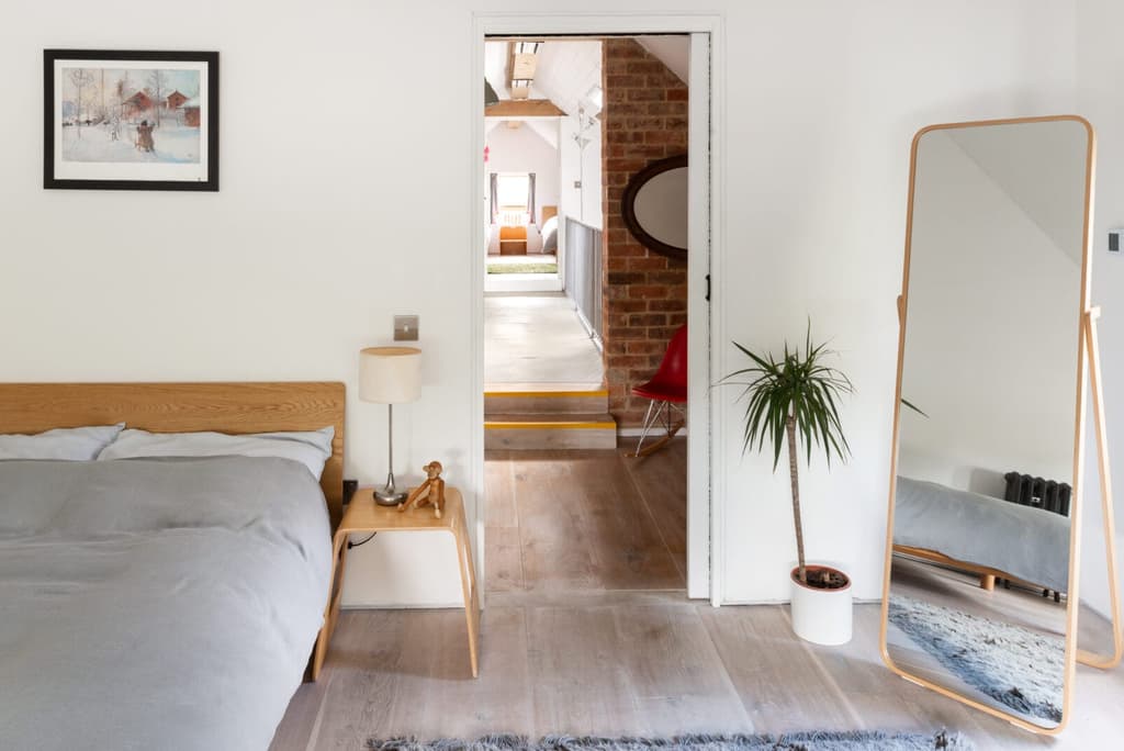 The kitchen dining room flows onto the garden via folding glass doors, while a steel staircase leads up to the mezzanine walkway connecting two bedrooms at either end of the first floor.