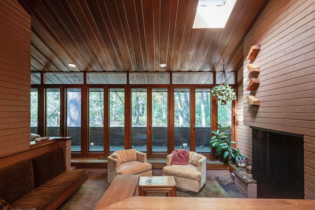The Great Room features tall ribbon windows, exposed brickwork on the fireplace and mahogany ceilings