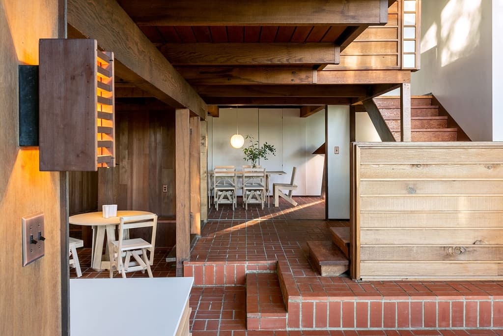The ground-floor of the Jean G Killion Residence features an flowing dining room, kitchen and lounge area which are loosely demarked by stepped levels