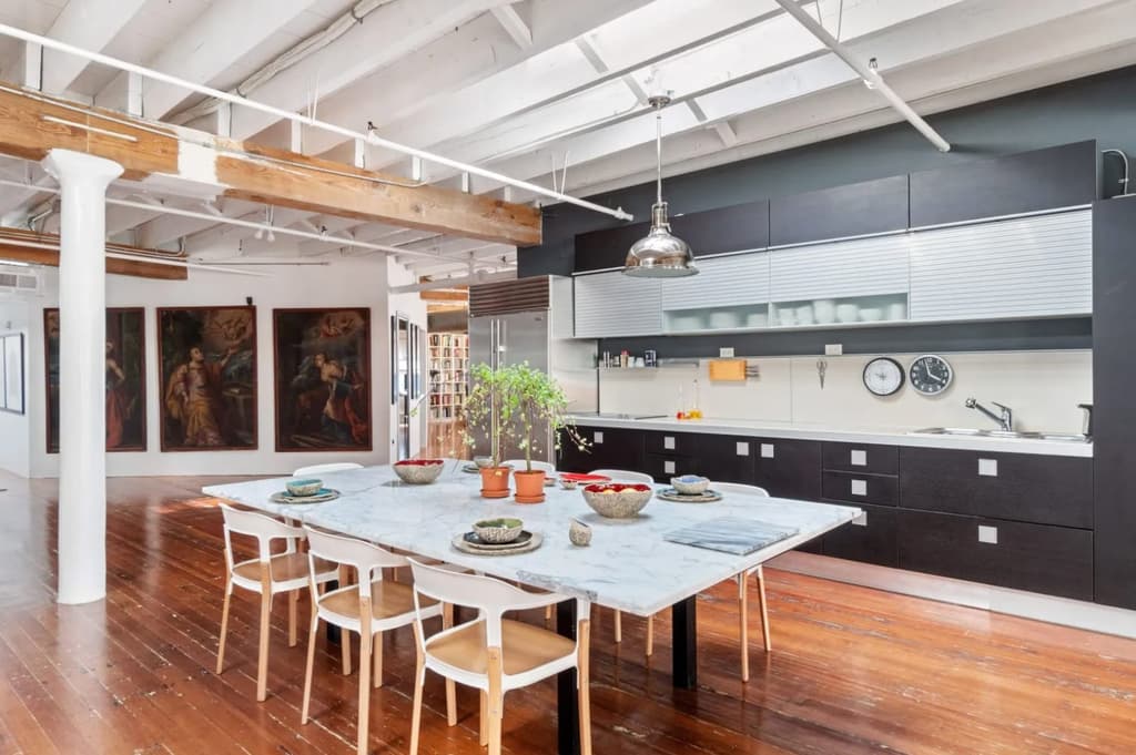 Iron and concrete colums, oak beams and raftered ceilings feature throughout. Meanwhile the kitchen is used as an informal divider to zone off an area of the open floorplan