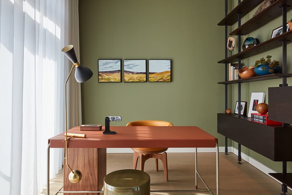The study area has a midcentury modern vibe thanks to mossy walls and timber shelving