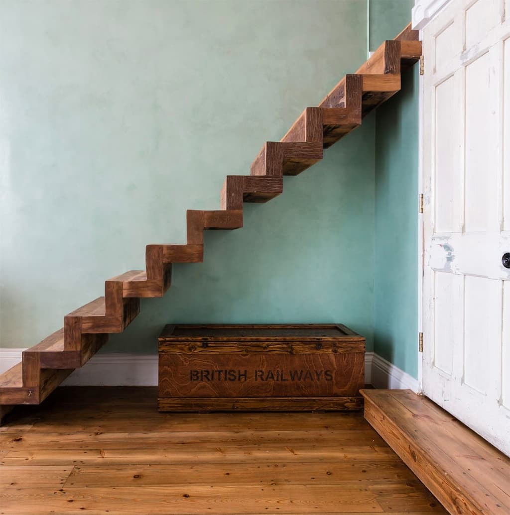 A floating timber staircase leads up the mezzanine level in the double-height bedroom