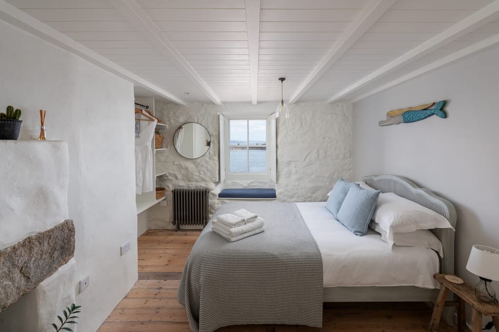 The main bedroom has painted stone walls and an original stone fireplace. Pine floorboards run underfoot.