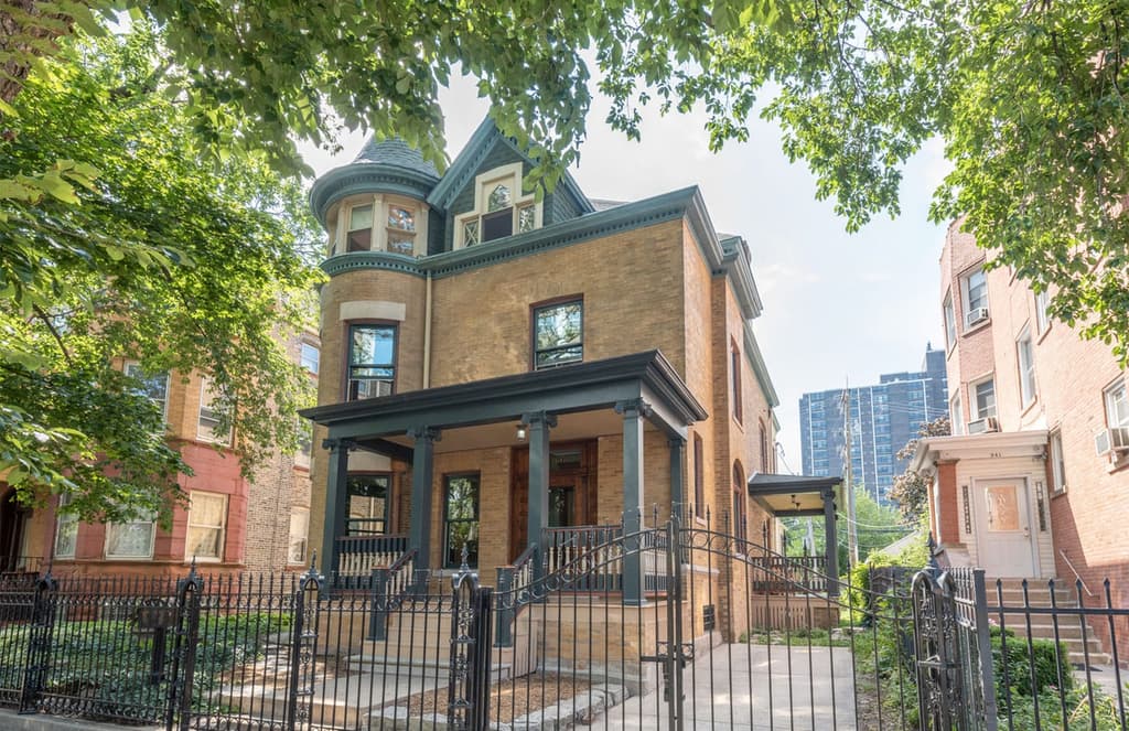 The exterior of the home features a corinthian column-supported timber porch and turreted roofline