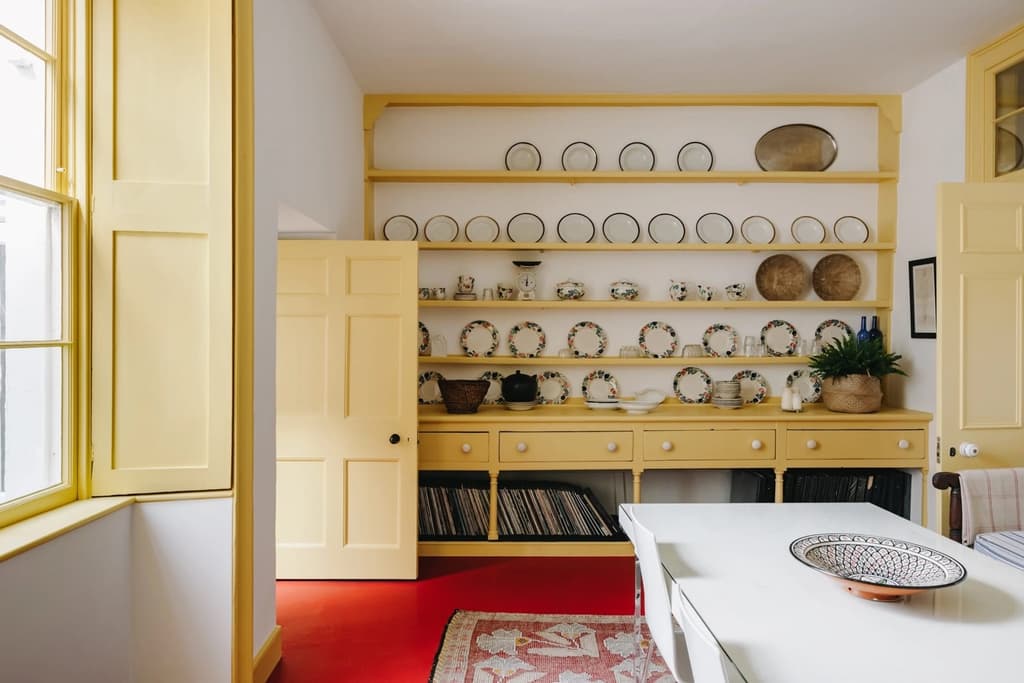 The kitchen has been modernised with veined marble countertops, while the pantry and dining room have cheerful yellow and green storage.