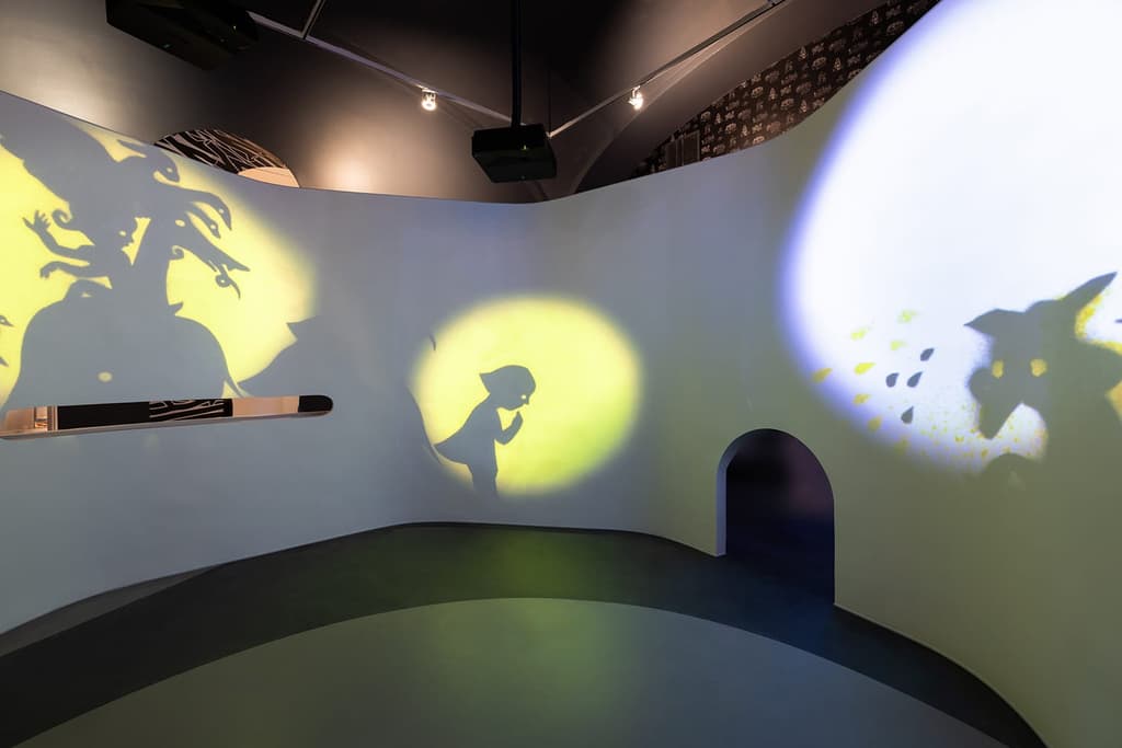 Pictured: the “Your Home, My Home” gallery in Building Stories, a curving space illuminated with shadow puppets. Photography: Elman Studio
