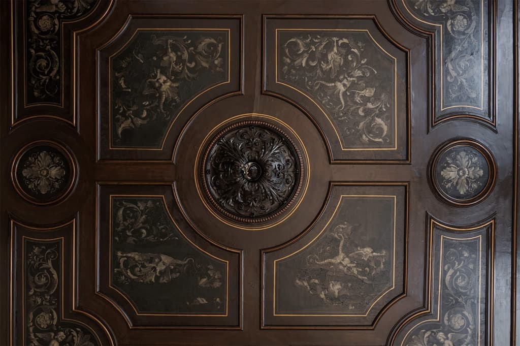 A decorative ceiling with moulding and frescoes