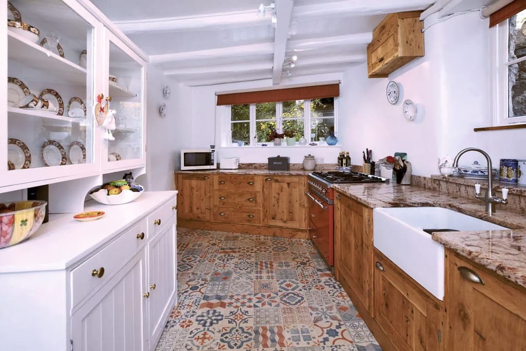 The renovated kitchen features patterned floor tiles, painted beams and pine cabinets