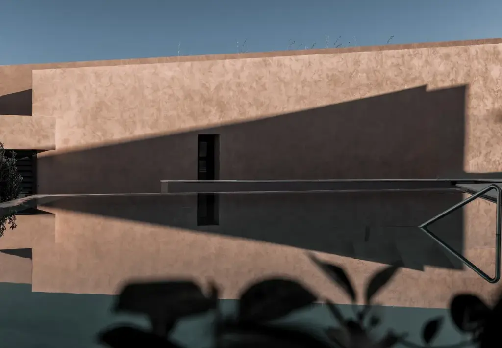 A view of the swimming pool, with the hotel's long rectilinear volumes reflected in the surface