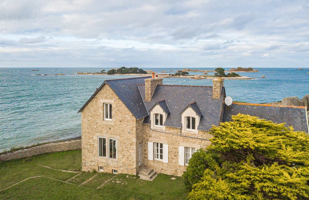 Anchored to a rocky spur, this granite home in Brittany has two wings
