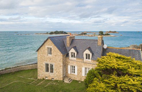 Anchored to a rocky spur, this granite home in Brittany has two wings